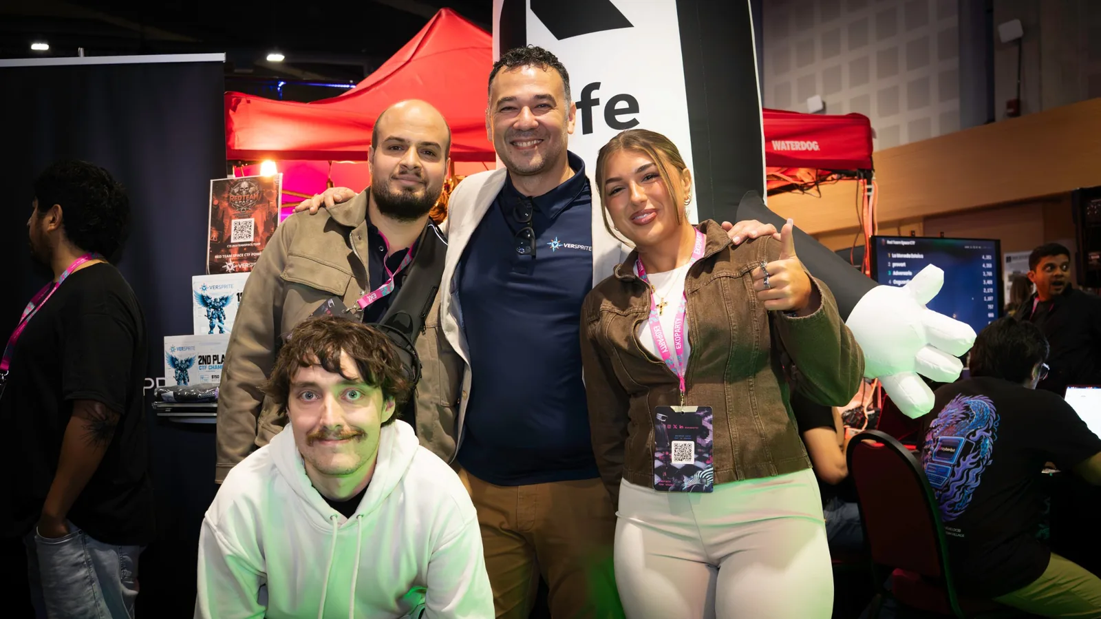 Equipo de la empresa posando sonriente frente a su stand en Ekoparty