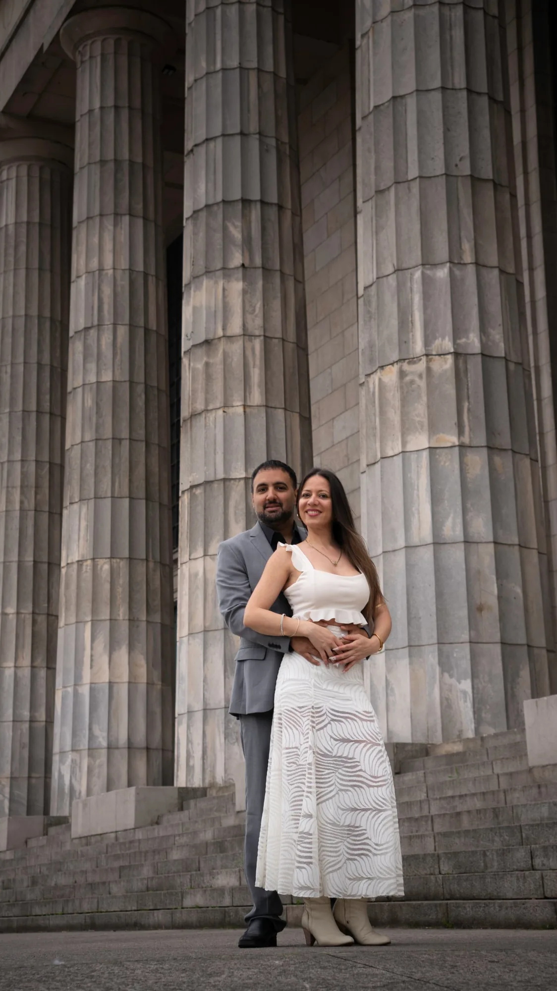 Novios abrazados y sonrientes en la escalinata de la Facultad de Derecho